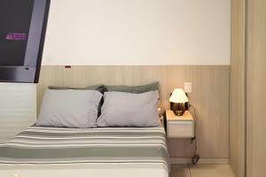 a bed with white pillows and a night stand with a lamp at Studio Top Life: Garagem | Wifi | Ar-condicionado NA1002 in Juiz de Fora