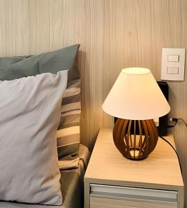 a lamp on a night stand next to a bed at Studio Top Life: Garagem | Wifi | Ar-condicionado NA1002 in Juiz de Fora