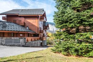 ein Holzhaus mit einem Baum davor in der Unterkunft Résidence Les Fermes du Soleil - maeva Home - Appartement 3 pièces 6 personnes Sélection MAE-1439 in Les Carroz d'Araches