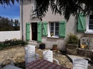 een tafel en stoelen voor een huis met groene luiken bij Gîte de France à Albussac 3 épis - Gîte de France 2 personnes 614 in Albussac