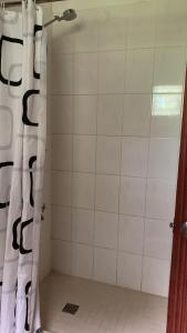 a shower with a black and white shower curtain at Canopy cottage in Honiara +4 photos
