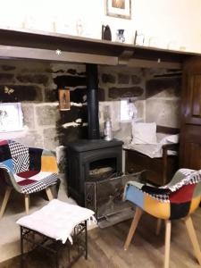 a living room with a stove and some chairs at Gîte de France à Sioniac 2 épis - Gîte de France 5 personnes MAE-9744 in Sioniac