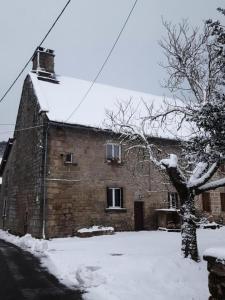 um velho edifício de tijolos com neve em Gîte de France Des alpagas 3 épis - Gîte de France 6 personnes 784 em Chaumeil