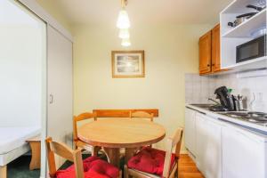 eine Küche mit einem Tisch und Stühlen im Zimmer in der Unterkunft Résidence Les Horizons d'Huez - maeva Home - Appartement 2 pièces 4 personn 59 in Huez