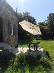 einen Picknicktisch mit einem Sonnenschirm im Hof in der Unterkunft Gîte de France La maisonnette 2 épis - Gîte de France 2 personnes 764 in Servières-le-Château