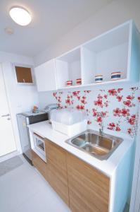 a kitchen with a sink and red flowers on the wall at Baan Im Em by little dragon in Hua Hin