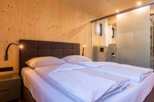 1 dormitorio con 1 cama grande con sábanas blancas en Kreischberg Pool Villas & Penthouses by ALPS RESORTS en Sankt Lorenzen ob Murau