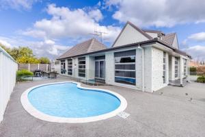 a house with a swimming pool in front of it at Business or Holiday 4 bedrooms house in Hamilton with pool and spa in Hamilton