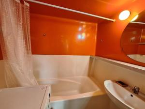 W łazience znajduje się wanna, umywalka i lustro. w obiekcie Résidence Tournavelles - 2 Pièces pour 5 Personnes 39 w mieście Arc 1800