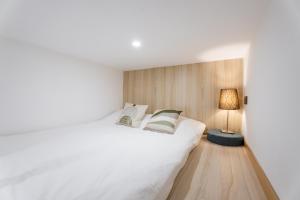 a bedroom with a large white bed and a lamp at Shanghai Hills&XING 1884 Family Homestay Near Line2 & Line12 West Nanjing Road in Shanghai