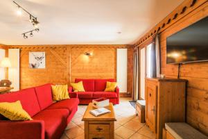 ein Wohnzimmer mit einem roten Sofa und einem Flachbild-TV in der Unterkunft Résidence Les Alpages de Reberty - maeva Home - Appartement 3 pièces 6 pers 26 in Les Menuires