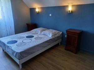 ein Bett in einem Zimmer mit zwei Nachttischen und einer blauen Wand in der Unterkunft Gîte de France Gratte bruyère 3 épis - Gîte de France 8 personnes 984 in Sérandon
