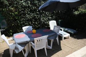 a table with chairs and an umbrella and a table with a fruit on it at Résidence HELIOVILLAGE - Maisons & Villas pour 4 Personnes 664 - Naturiste in Cap d'Agde