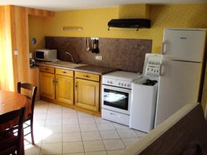 a kitchen with a white stove and a refrigerator at Gîte de France La maison de louise 3 épis - Gîte de France 4 personnes MAE-0014 in La Bitarelle