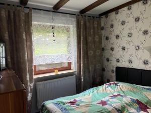 a bedroom with a bed and a window with curtains at Feriendorf am Hohen Bogen - Haus 66 in Arrach