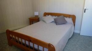 a bedroom with a wooden bed with two pillows at Gîte de France à Curemonte 2 épis - Gîte de France 4 personnes MAE-0004 in Curemonte