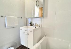 a white bathroom with a sink and a bath tub at Résidence Home Club - Studio pour 4 Personnes 71 in Tignes