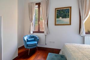 a bedroom with a blue chair and a window at Palazzo Boito Luxury Apartment Lido Venice view Loc14132 in Venice-Lido