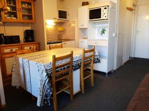 Una cocina con una mesa con sillas y un refrigerador. en Résidence Fond Blanc - Studio pour 4 personnes à Arc 2000 proche des commerces et des pistes MAE-1788, en Arc 2000