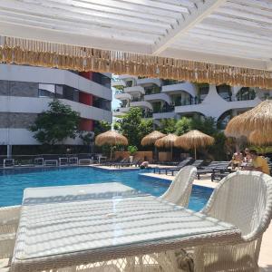 een zwembad met een tafel en rieten parasols bij New Eva Unique Luxury Apartament in Mamaia Nord – Năvodari