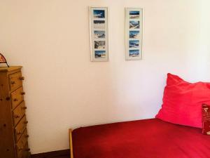 a bedroom with a red pillow and pictures on the wall at Résidence Rond-point Des Pistes Iii - 2 Pièces pour 4 Personnes 98 in Val-d'Isère