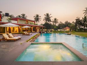 a swimming pool with chairs and a resort at Kidena House in Goa Velha