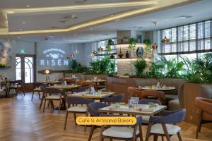 un ristorante con tavoli, sedie e piante di Grand Heights Hotel Apartments a Dubai