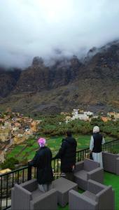 3 personnes debout sur un balcon donnant sur une montagne dans l'établissement Season Inn Hotel_Bald Sayt, à Rustāq