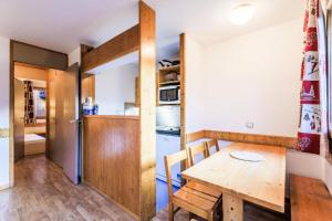 a kitchen and dining room with a wooden table and chairs at Résidence Les Brigues - maeva Home - Appartement 2 pièces 6 personnes Confo 92 in Courchevel