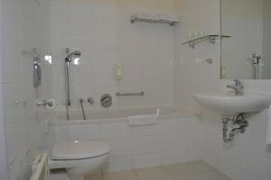 ein Badezimmer mit einem Waschbecken, einer Badewanne und einem WC in der Unterkunft Aparthotel Austria Suites in Prag