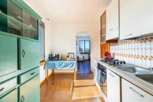 una cocina con armarios verdes y fregadero en Villa due Archi, en S'Archittu
