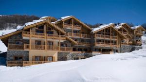 un grand bâtiment en bois avec de la neige au sol dans l'établissement Les Chalets du Gypse - Appartement CHALET GYPSE C16 pour 10 Personnes 43, à Saint-Martin-de-Belleville