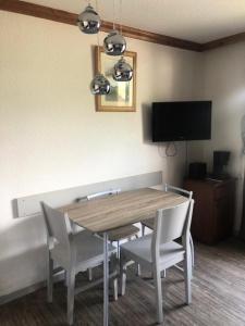 a dining room table with white chairs and a television at Résidence Les Bergers - maeva Home - Studio 4 personnes - Sélection MAE-0234 in LʼHuez