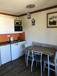 a small kitchen with a wooden table and chairs at Résidence Les Bergers - maeva Home - Studio 4 personnes - Sélection MAE-0234 in LʼHuez