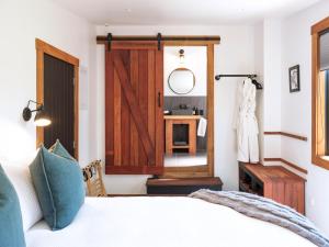 a bedroom with a bed with a wooden door and a mirror at Black Cottage Boutique Acommodation in Havelock North