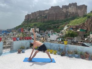 a man doing a yoga pose on top of a roof at Anne Guest House in Jodhpur