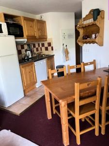 a kitchen with a wooden table with chairs and a refrigerator at Résidence Les Cristallines - 3 Pièces pour 6 Personnes 114 in Orcières