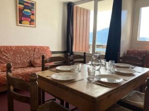 a wooden table with plates and glasses and a couch at Résidence Rond-point-pistes I - Studio pour 6 Personnes 271 in Orcières