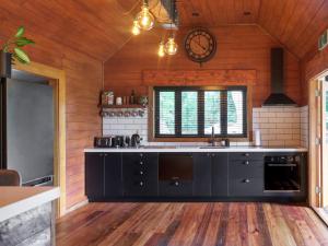 a kitchen with black cabinets and a clock on the wall at Black Cottage Boutique Acommodation in Havelock North