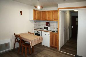a small kitchen with a table and a microwave at Résidence LE PERESCUELLE - Studio pour 4 Personnes 624 in Les Orres