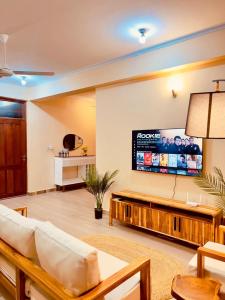 a living room with a couch and a tv on a wall at Pishon Home in Dar es Salaam