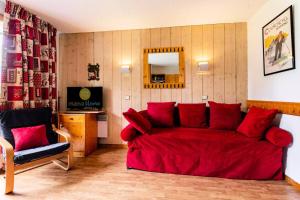 a living room with a red couch and a television at Résidence Les Brigues - maeva Home - Appartement 2 Pièces 6 Personnes - Con 98 in Courchevel