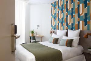 a bedroom with a large bed with a colorful headboard at Hôtel Suzane in Angers
