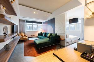 a living room with a green couch and a bed at The Aberdeen Harbour by Ovolo in Hong Kong