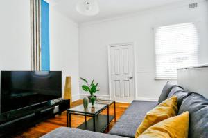 a living room with a couch and a tv at Family Friendly 3 Bedroom House Glebe 2 E-Bikes Included in Sydney