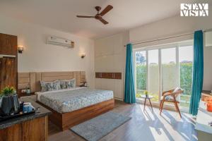 a bedroom with a bed and a large window at Hriday Bhoomi with Pool at Jim Corbett by StayVista in Jhirna