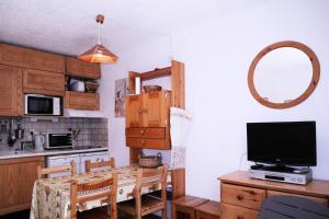 a kitchen with a table with a television on a counter at Résidence LE POUZENC - Studio pour 6 Personnes 994 in Les Orres