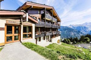 a building on a hill with mountains in the background at Résidence Les Brigues - maeva Home - Appartement 2 Pièces 6 Personnes – C 02 in Courchevel