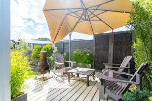 een patio met een tafel en stoelen en een parasol bij Sun Kissed Pool Villa - Mangawhai Holiday Home in Mangawhai