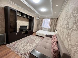 een slaapkamer met een bed, een bank en een tv bij Apartmens in Complex Almaly 83-51 in Alma-Ata